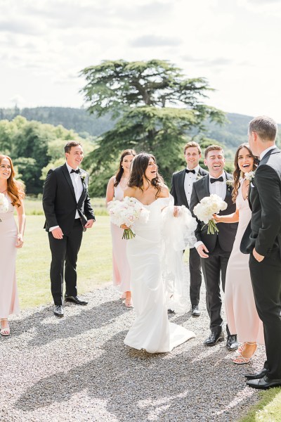 bride groom groomsmen and bridesmaids outside in the sunshine on the grass