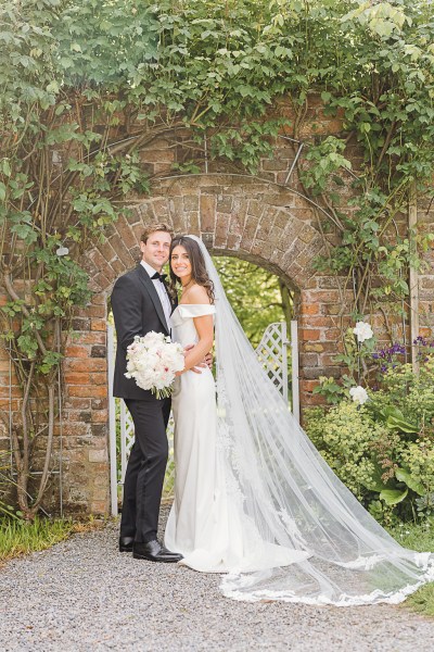 bride and groom hug and embrace in garden flower setting