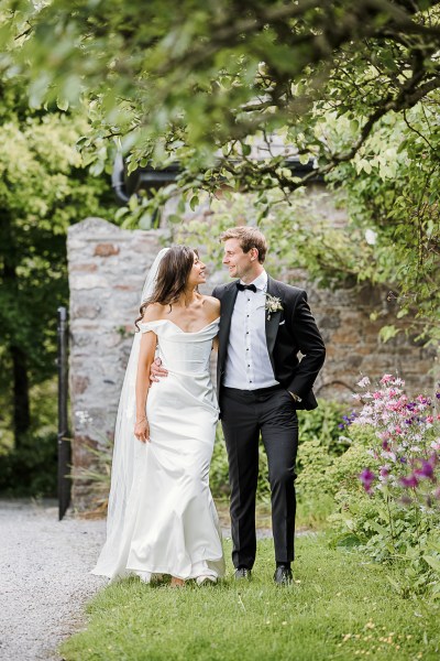 bride and groom look at each other in garden flower setting