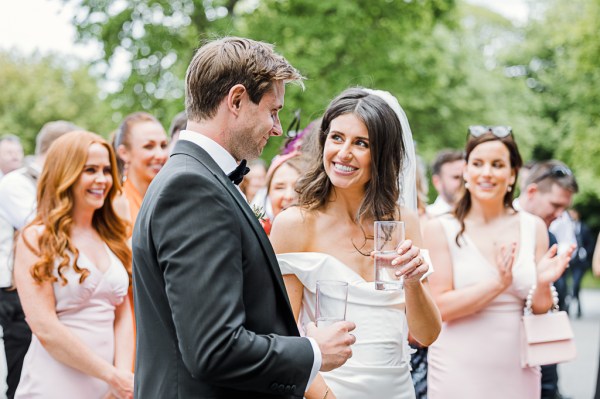 bride and groom look at each other they hold glass of champagne