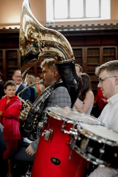 wide shot of wedding band playing trumpet saxophone and trombone down the aisle band is also playing drums