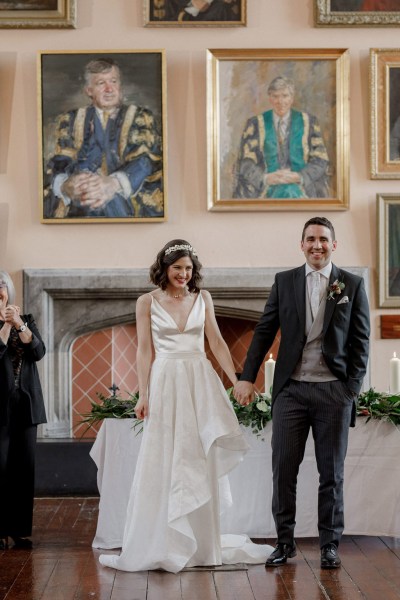 bride and groom hold hands at top of alter