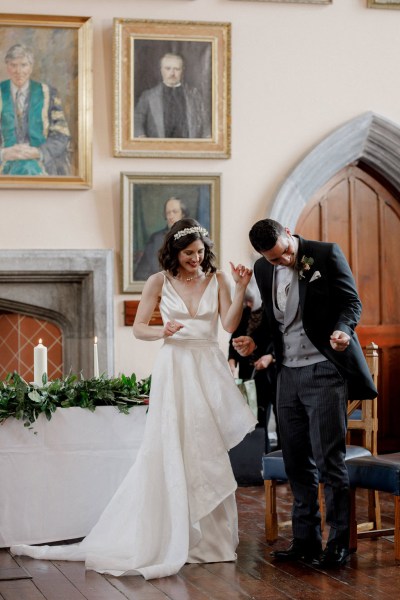 bride and groom hold hands smiling at alter