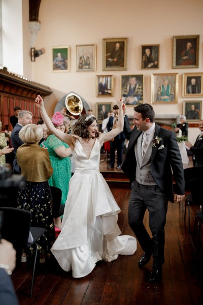 bride and groom bouquet in the air all smiles as they exit ceremony setting