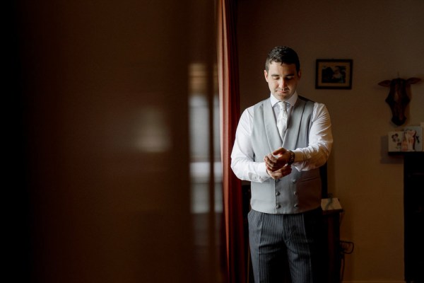 groom gets ready in groom fixes watch or cufflinks