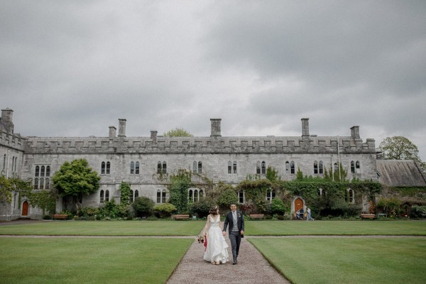 wide shot of bride and groom walking the pathway with venue in the background