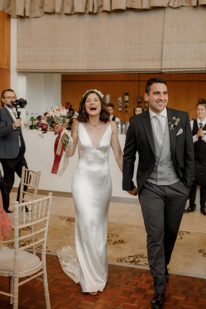 bride and groom enter the dining room ballroom holding hands guests clap