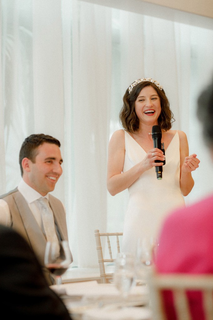 bride giving speech into microphone laughing