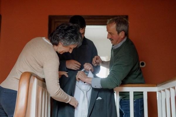 mother and father help groom get ready for wedding