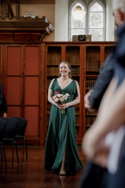 bridesmaids in green walks down the aisle