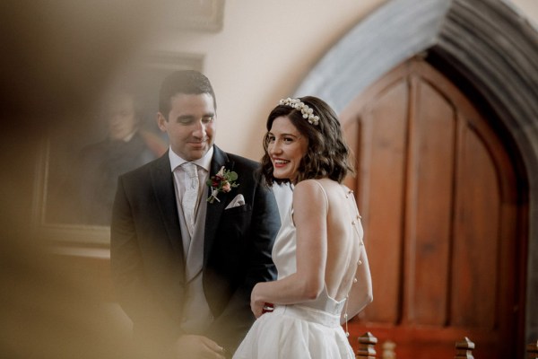 bride and groom stand at alter smiling