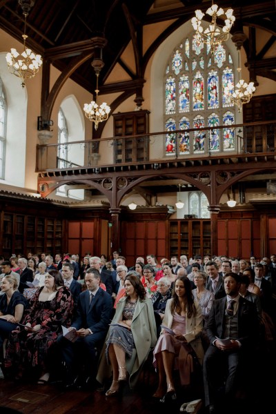 shot of guests seated during wedding ceremony church setting bridesmaids at front row