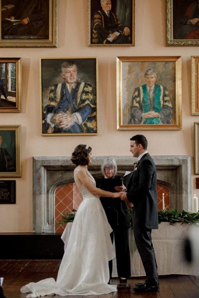 bride and groom smile hold hands at the alter they read their vows