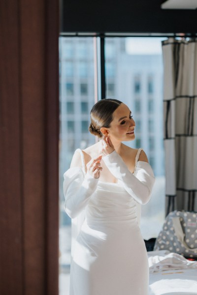 bride puts on her wedding earrings