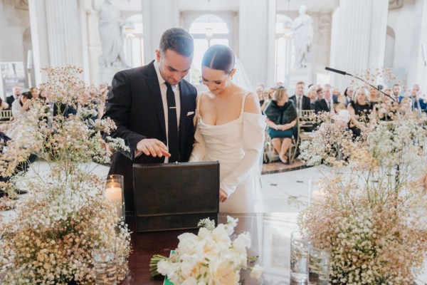 bride and groom stand at table covered in flowers