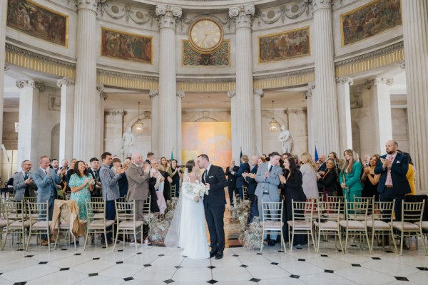 bride and groom kiss and exit ceremony as guests clap