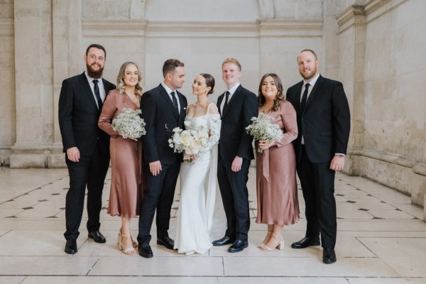 bride and groom look at each other in front of groomsmen and bridesmaids