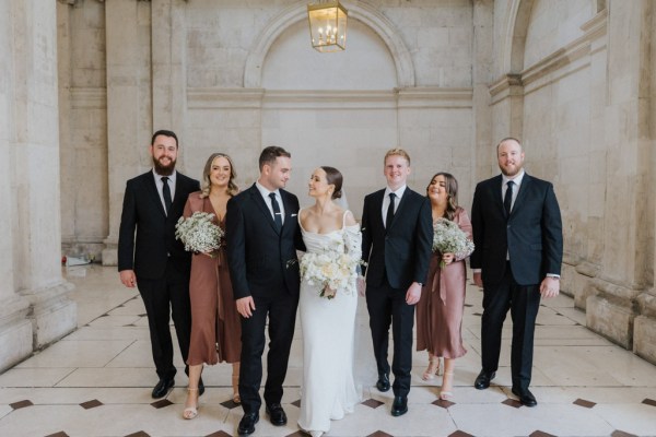 bride and groom look at each other in front of groomsmen and bridesmaids