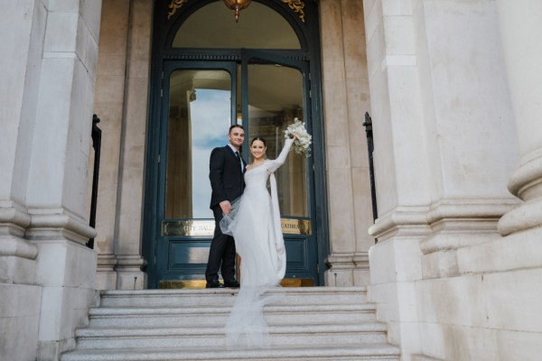 bride and groom are standing on the steps to wedding venue ceremony bouquet in the air