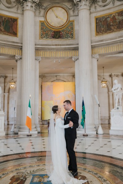 bride and groom dance on the tiled floor in large pillared room