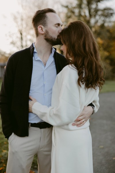 groom kisses bride on forehead in garden forest setting