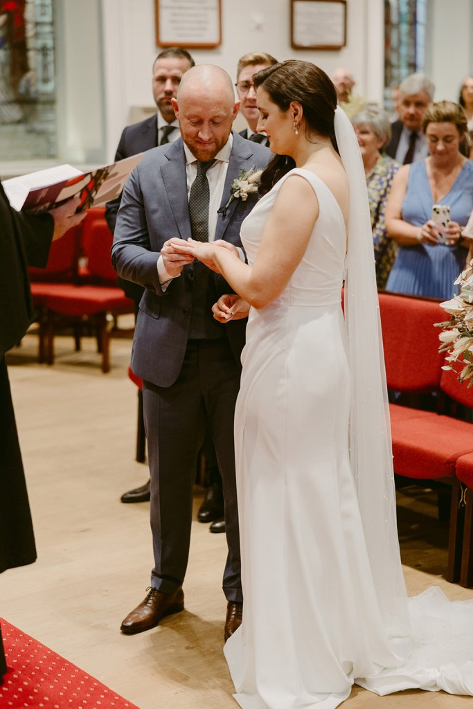 bride and groom exchange wedding rings at alter