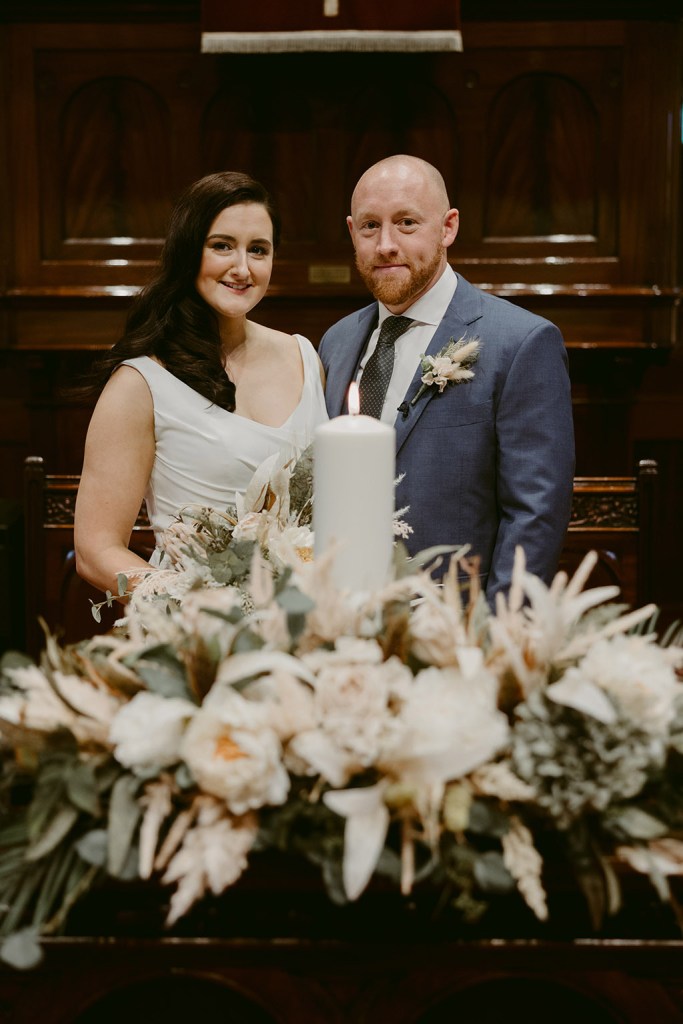 bride and groom in front of lighted candles and bouquet/flowers