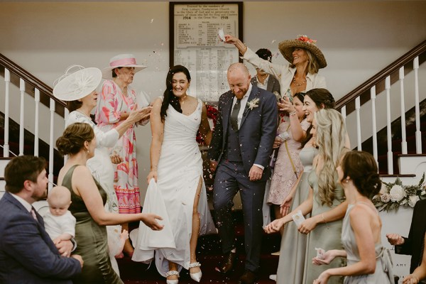 guests bridesmaids react to couple bride and groom on staircase