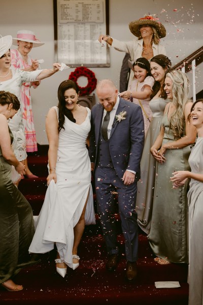 guests bridesmaids react to couple bride and groom on staircase