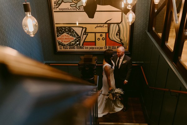 bride and groom stand in corner of pub holding hands