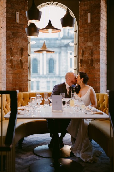 bride and groom kiss at table