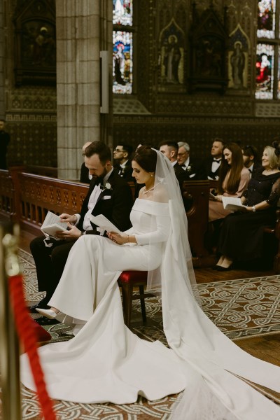 bride and groom sit at top of alter setting in church