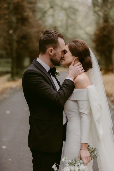 bride and groom kiss on pathway to forest garden setting