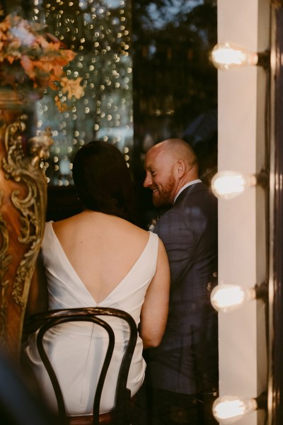 bride and groom sit at table in pub setting from behind