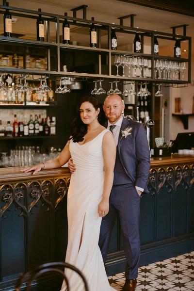 bride and groom stand at bar