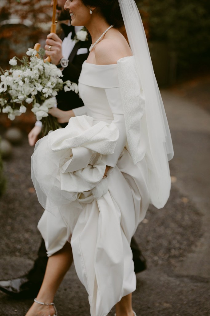 bride and groom walk together she holds up her train as she walks