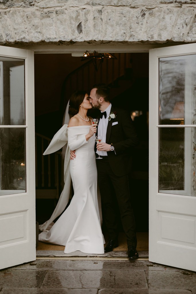 bride and groom are kissing at entrance to wedding venue