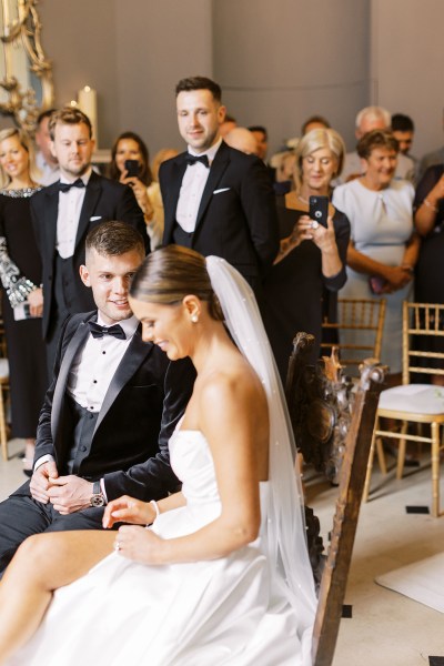 bride and groom face each other she wears veil at top of aisle