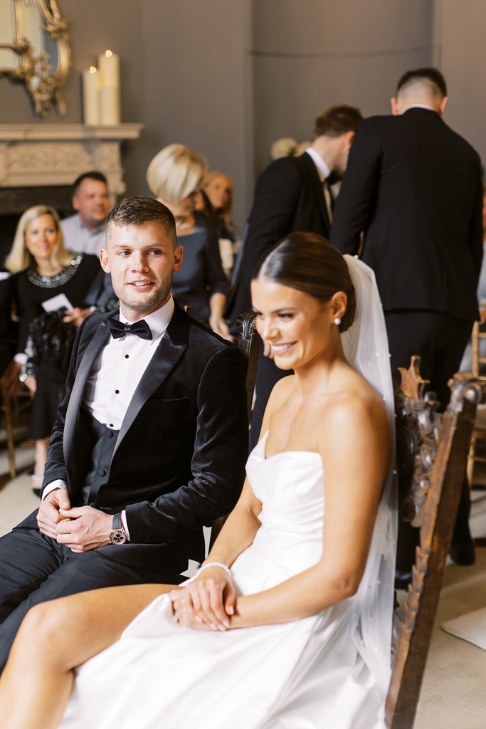 bride and groom face each other she wears veil at top of aisle she smiles