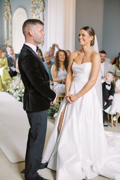 bride and groom holding hands smiling standing at top of alter setting