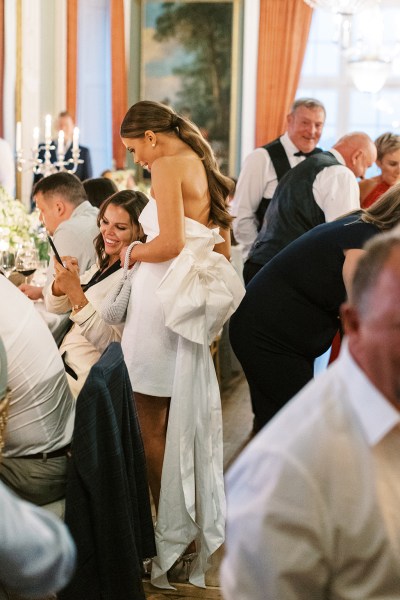 bride stands chatting to guests at table