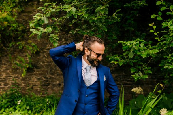 man in blue suit poses in garden