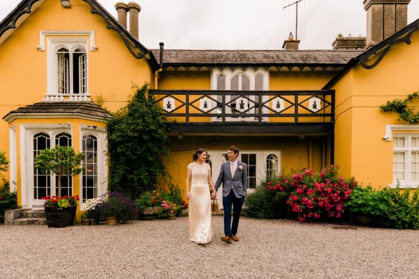 bride and groom hold hands outside of wedding venue walking towards camera