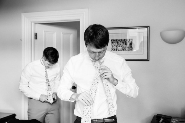 black and white groom getting ready putting on tie