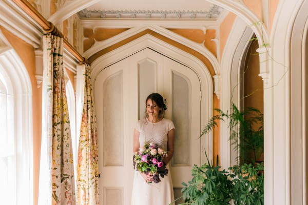 bride standing underneath archway to wedding venue