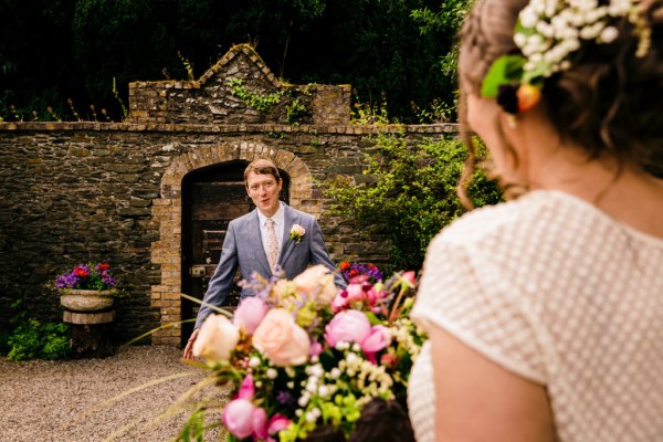 groom awaits his bride in garden hair detail accessories he turns around