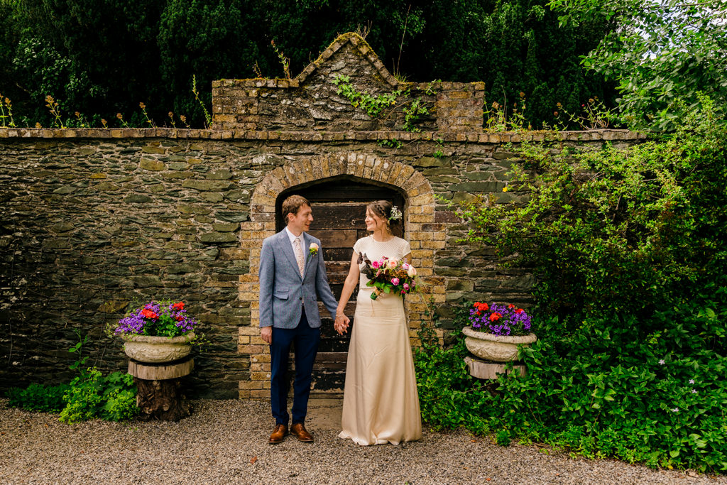 bride and groom look at each other in garden holding hands