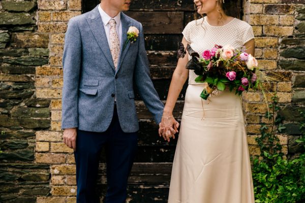 bride and groom look at each other in garden holding hands