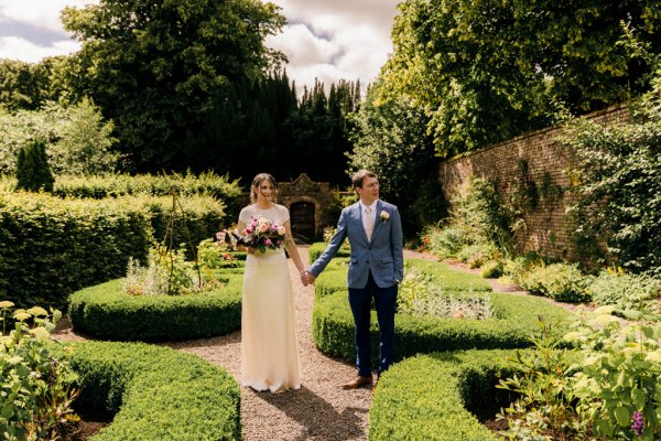 bride and groom walk the gardens down pathways trees and flowers