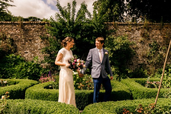 bride and groom walk the gardens she holds bouquet